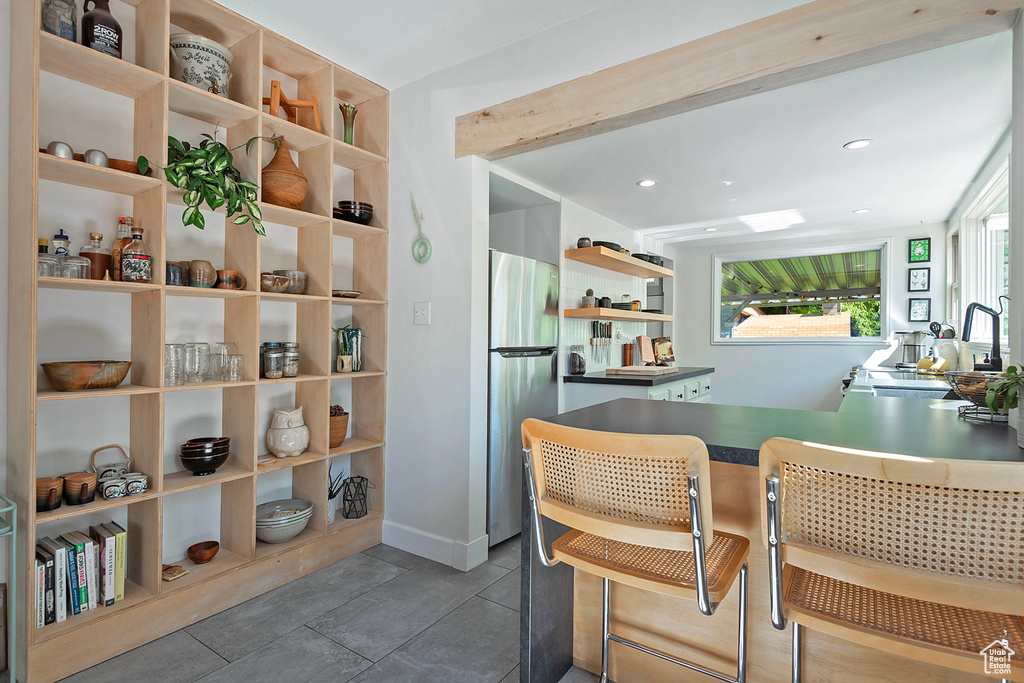 Kitchen with open shelves, freestanding refrigerator, a sink, recessed lighting, and a kitchen breakfast bar
