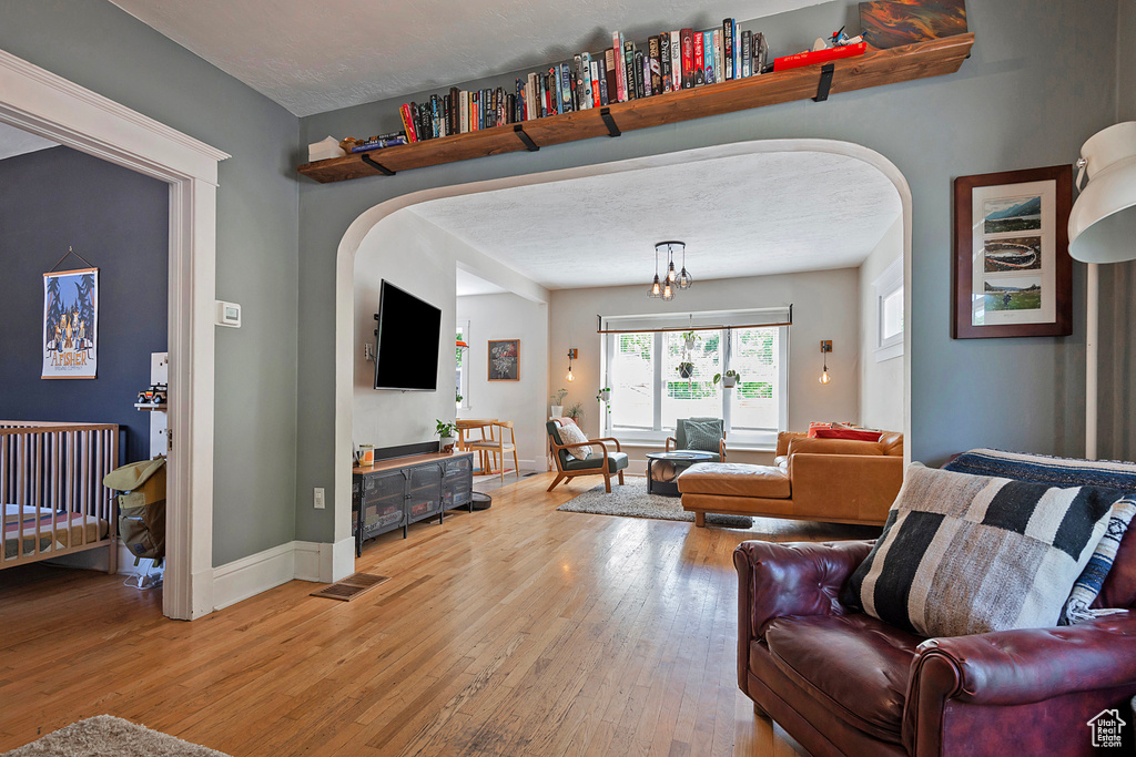 Living room featuring arched walkways, light wood-type flooring, and baseboards
