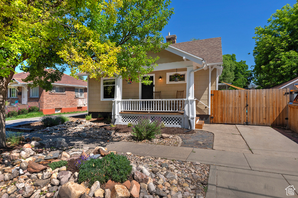View of front of home with a porch, a gate, a chimney, and roof with shingles