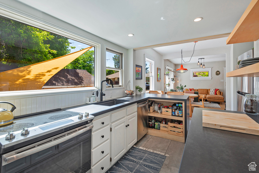 Kitchen featuring stainless steel appliances, a sink, white cabinets, recessed lighting, and a peninsula