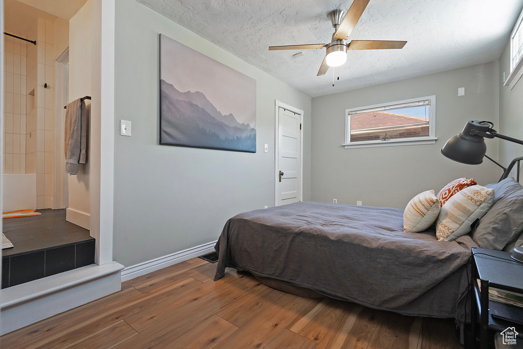 Bedroom featuring wood-type flooring, a textured ceiling, a ceiling fan, and baseboards