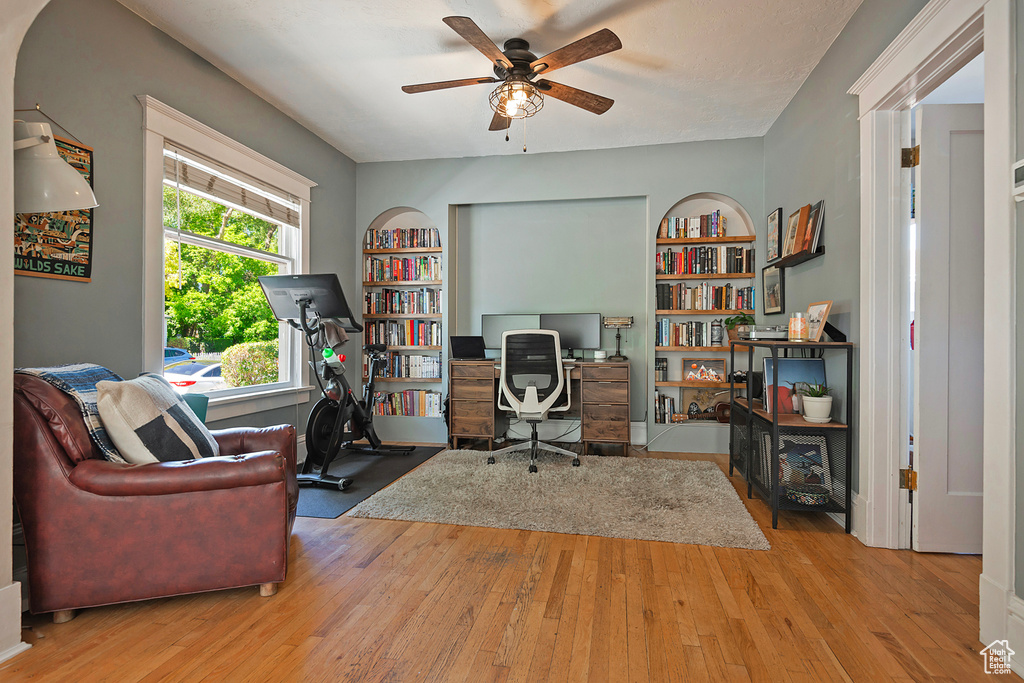 Office with a ceiling fan, wood-type flooring, and built in features