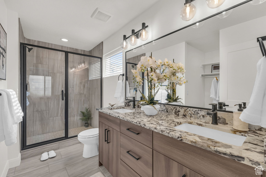 Bathroom with double vanity, toilet, a stall shower, and recessed lighting