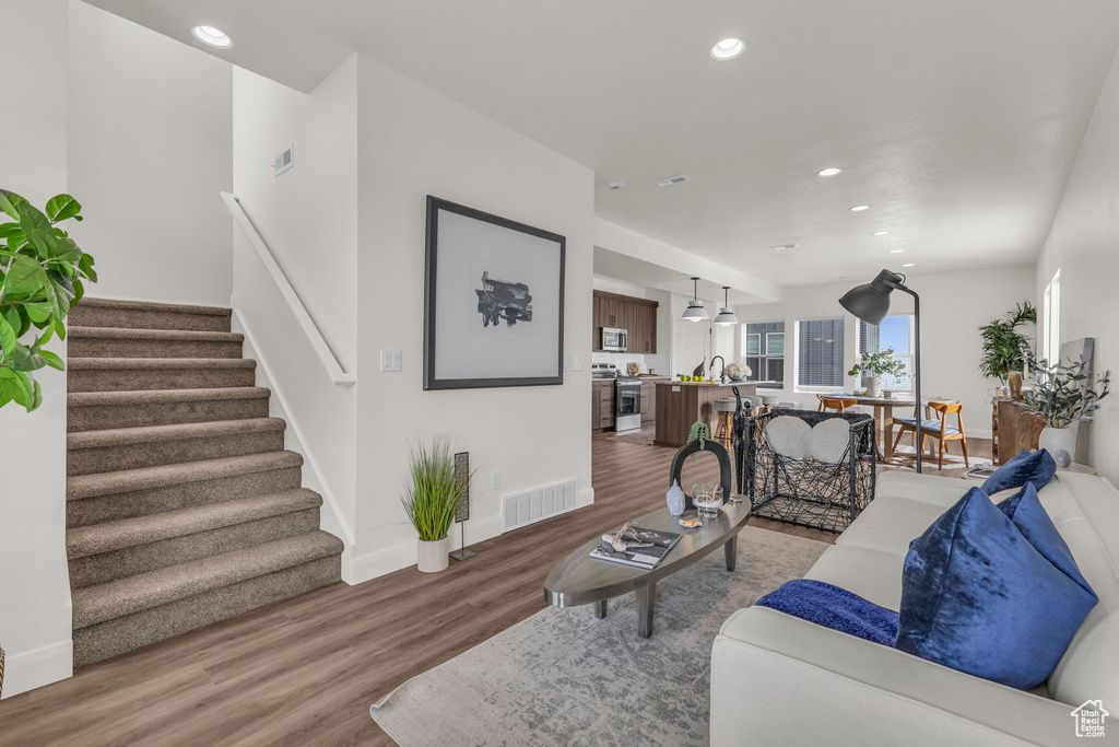 Living room with light wood-style flooring, recessed lighting, stairs, and baseboards