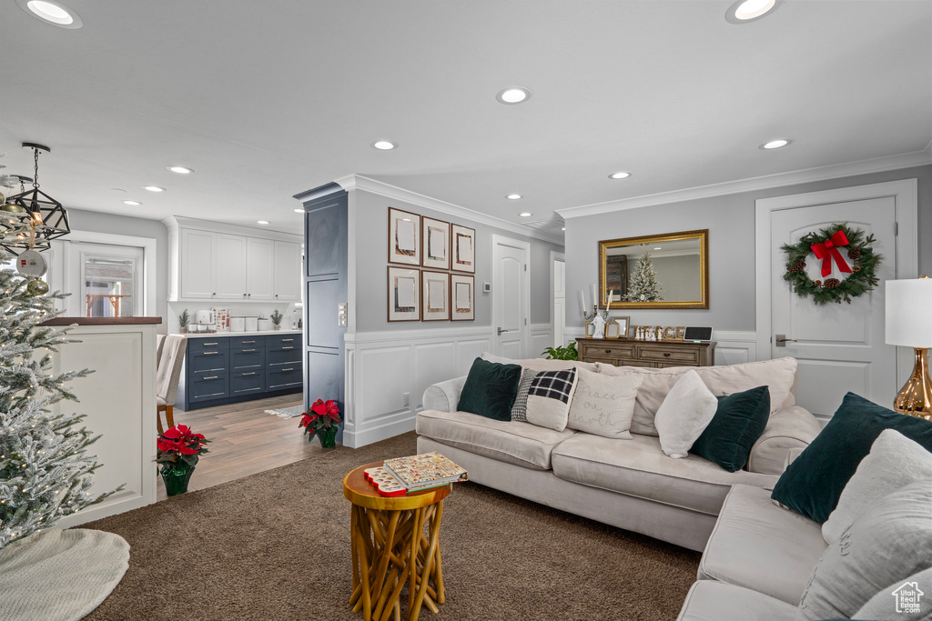 Living area featuring a decorative wall, ornamental molding, recessed lighting, wood finished floors, and wainscoting