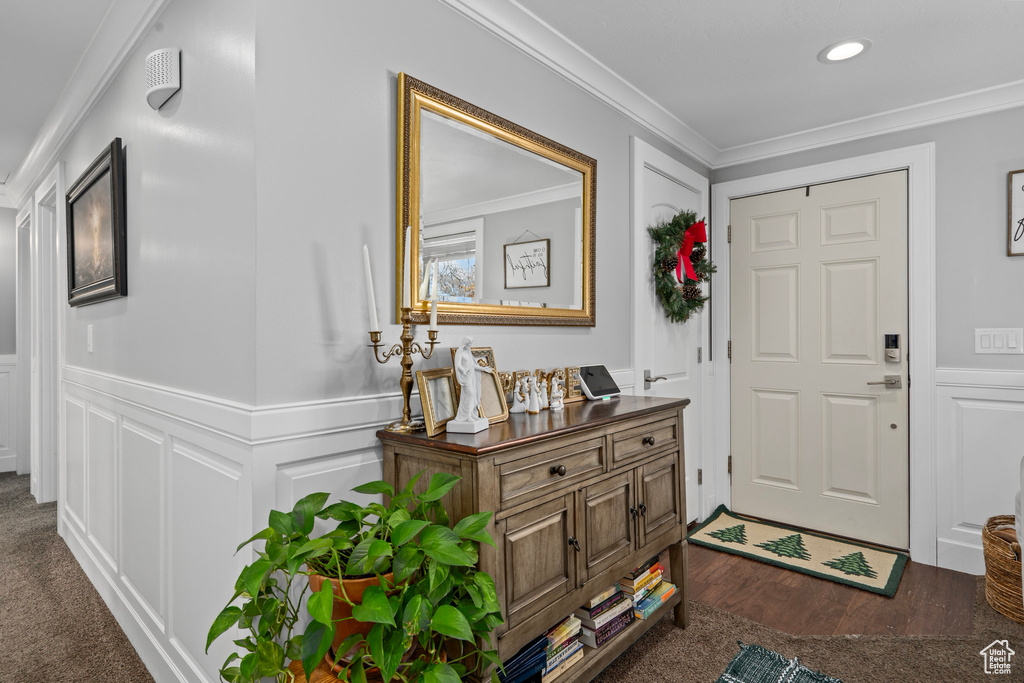 Entrance foyer featuring ornamental molding, a decorative wall, a wainscoted wall, recessed lighting, and dark wood-type flooring