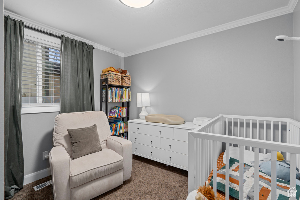 Bedroom featuring crown molding, baseboards, a crib, and carpet flooring