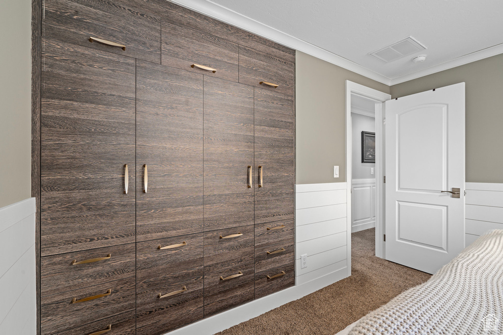 Unfurnished bedroom featuring carpet, wainscoting, and crown molding