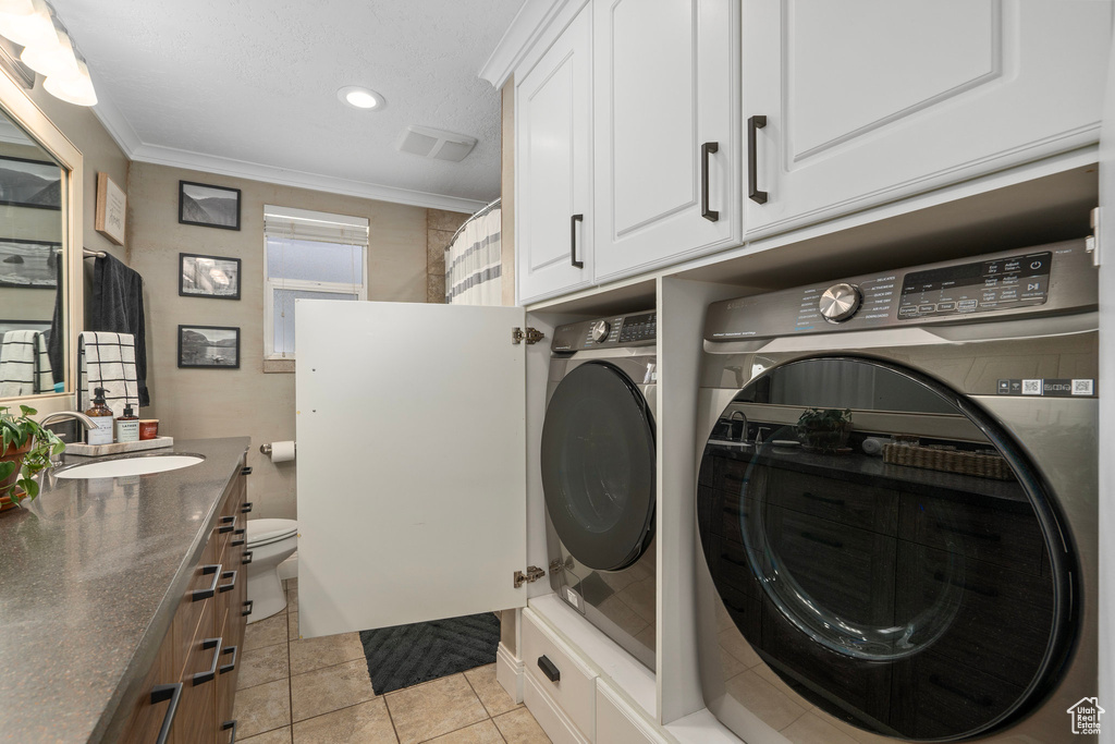 Washroom with washing machine and clothes dryer, crown molding, light tile patterned flooring, and recessed lighting