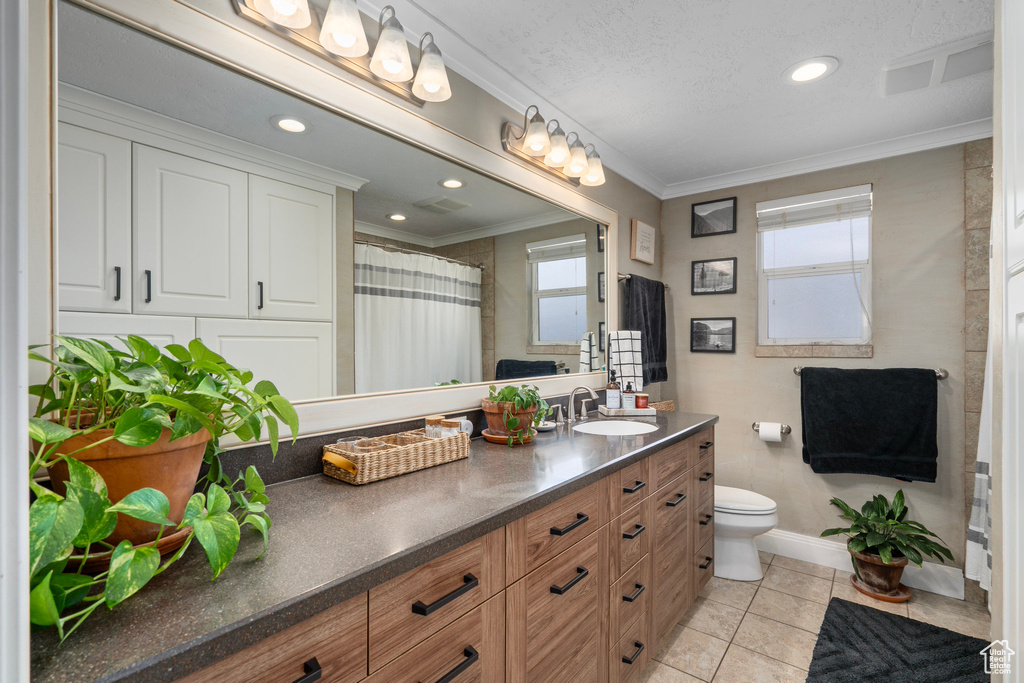 Bathroom with vanity, crown molding, baseboards, toilet, and recessed lighting