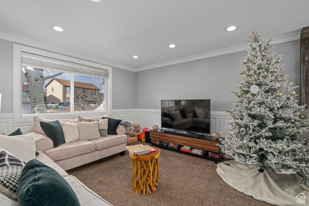 Carpeted living area with a decorative wall, wainscoting, recessed lighting, and ornamental molding