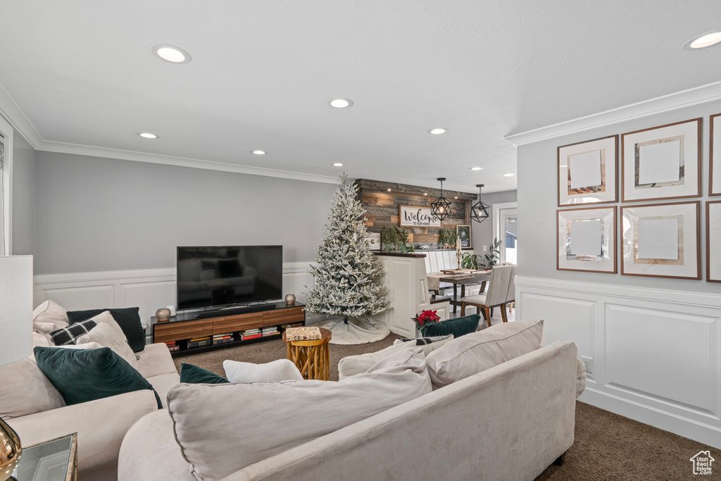 Living area featuring a decorative wall, ornamental molding, and dark colored carpet