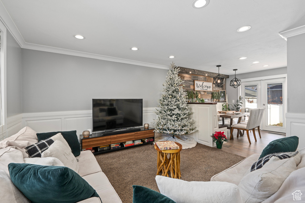 Living area with recessed lighting, wainscoting, crown molding, and a decorative wall