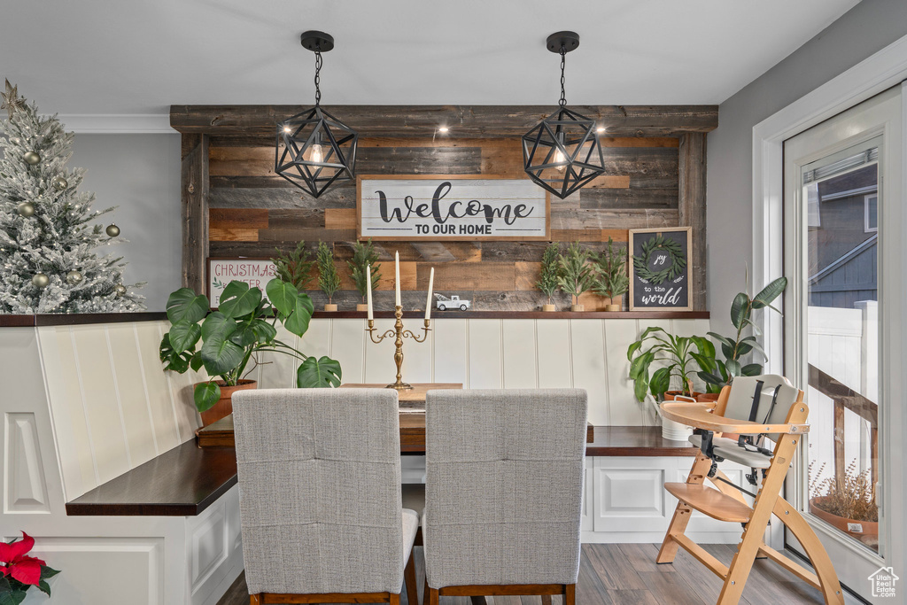 Dining room featuring dark wood-style floors, wood walls, and ornamental molding
