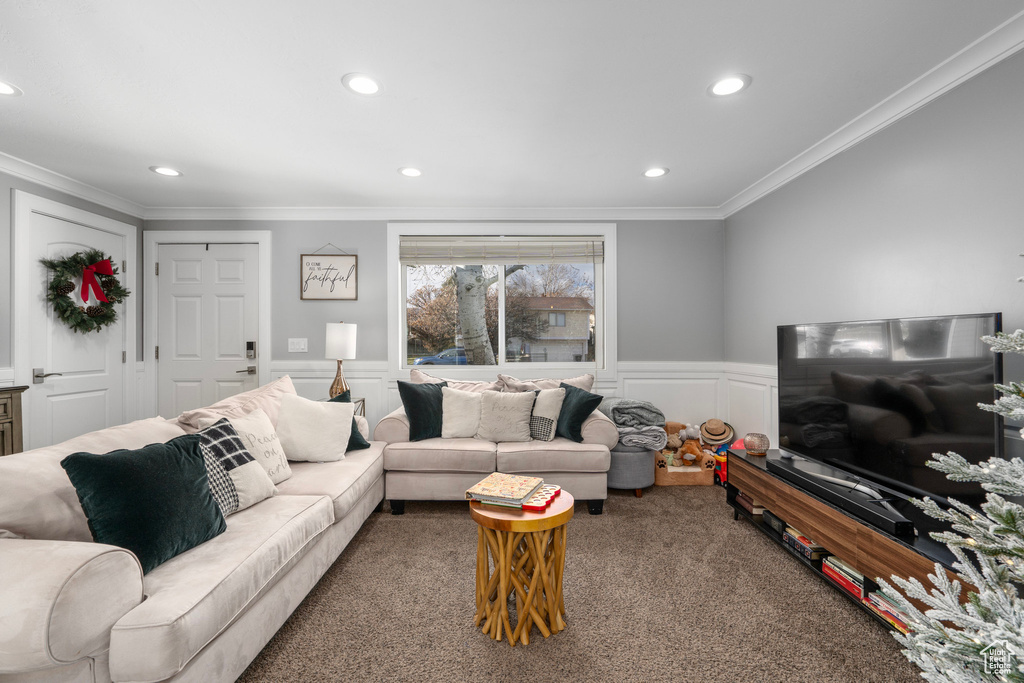 Carpeted living area featuring a decorative wall, recessed lighting, and crown molding