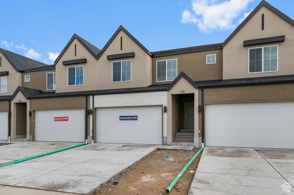 View of property with stucco siding, an attached garage, and driveway
