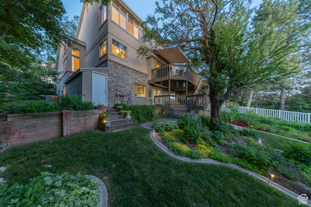 Back of property with stucco siding, stone siding, and a wooden deck