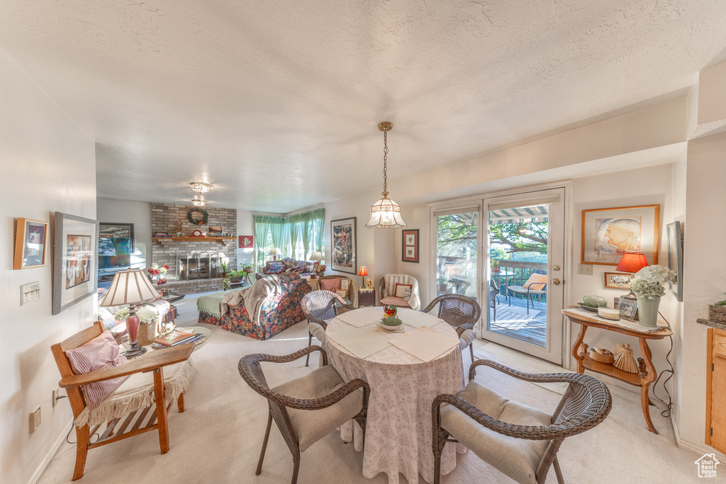 Dining area featuring light colored carpet, a fireplace, baseboards, and a textured ceiling
