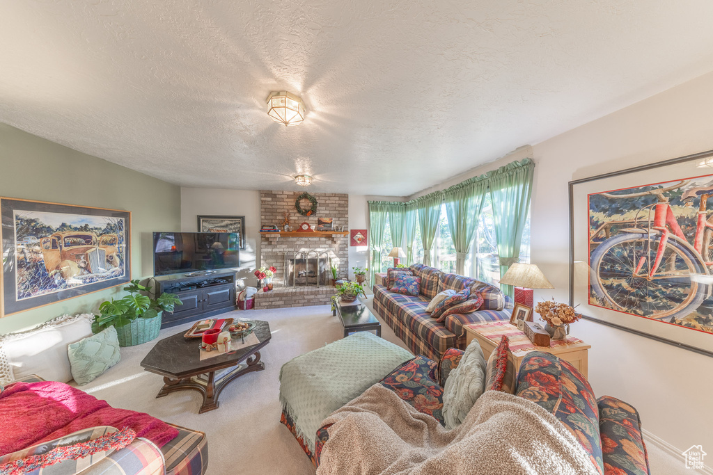 Living room with carpet, a textured ceiling, and a brick fireplace