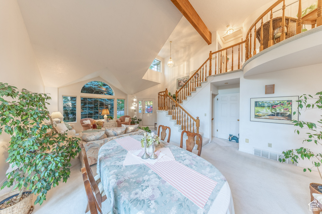 Dining space with carpet flooring, high vaulted ceiling, stairs, and beam ceiling
