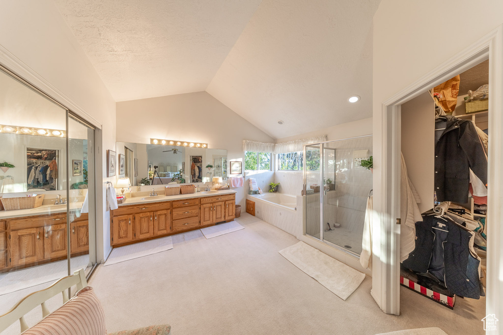 Full bath with a garden tub, a stall shower, double vanity, vaulted ceiling, and a walk in closet