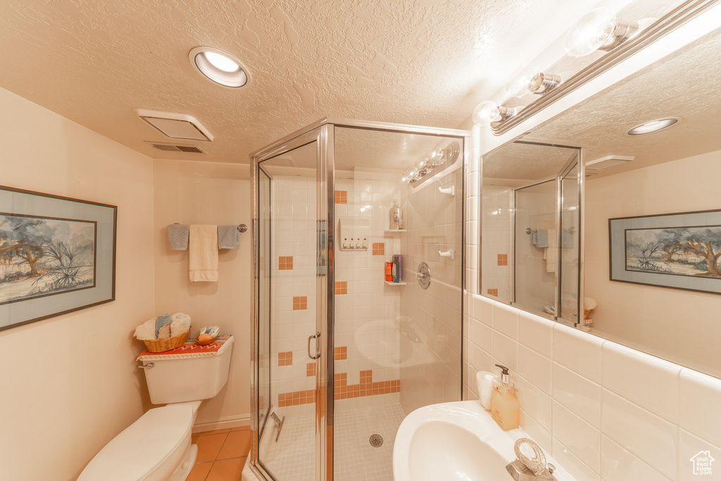 Full bath featuring a textured ceiling, toilet, a shower stall, tile patterned floors, and recessed lighting