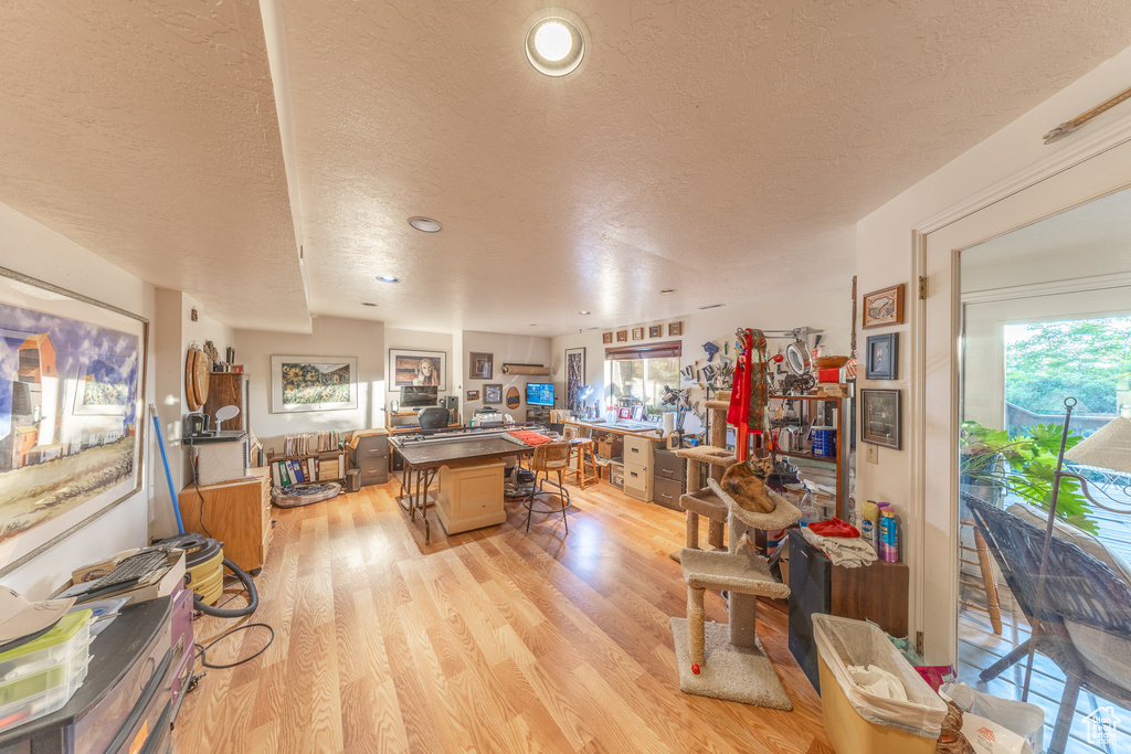 Kitchen featuring a textured ceiling, a center island, open floor plan, light wood finished floors, and a breakfast bar area