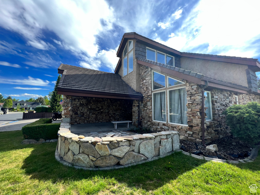 Rear view of house with stone siding and a yard
