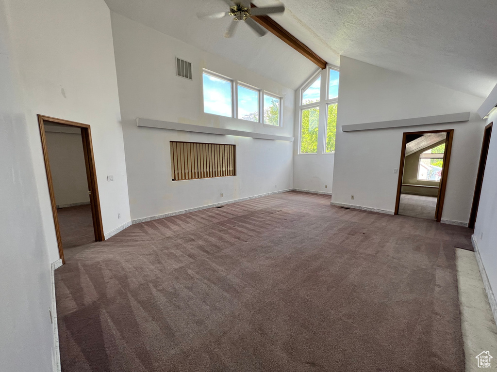 Unfurnished living room featuring carpet flooring, high vaulted ceiling, beamed ceiling, a ceiling fan, and baseboards
