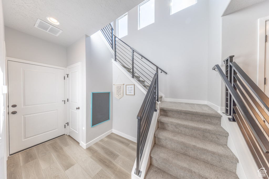 Stairs with wood finished floors, baseboards, and a textured ceiling