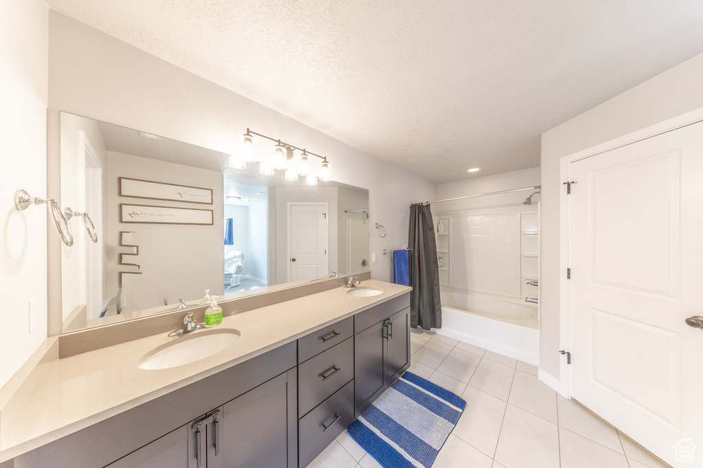 Full bath with double vanity, shower / bath combination with curtain, tile patterned flooring, and a textured ceiling