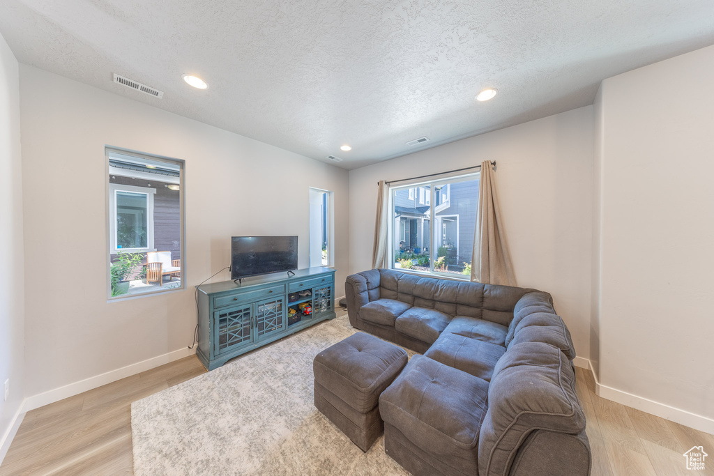 Living room with wood finished floors, baseboards, recessed lighting, and a textured ceiling