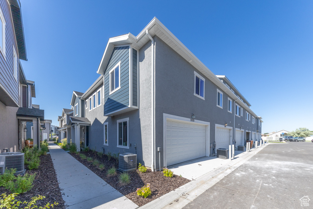 View of home\\\'s exterior featuring central air condition unit, a residential view, a garage, and stucco siding