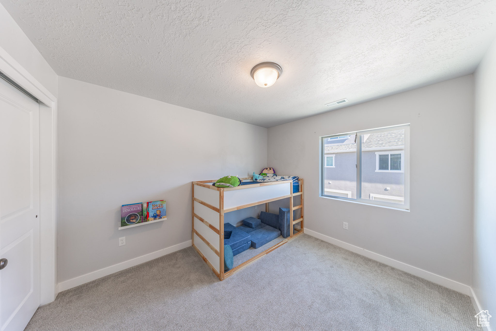 Bedroom featuring a textured ceiling, carpet, baseboards, and a closet