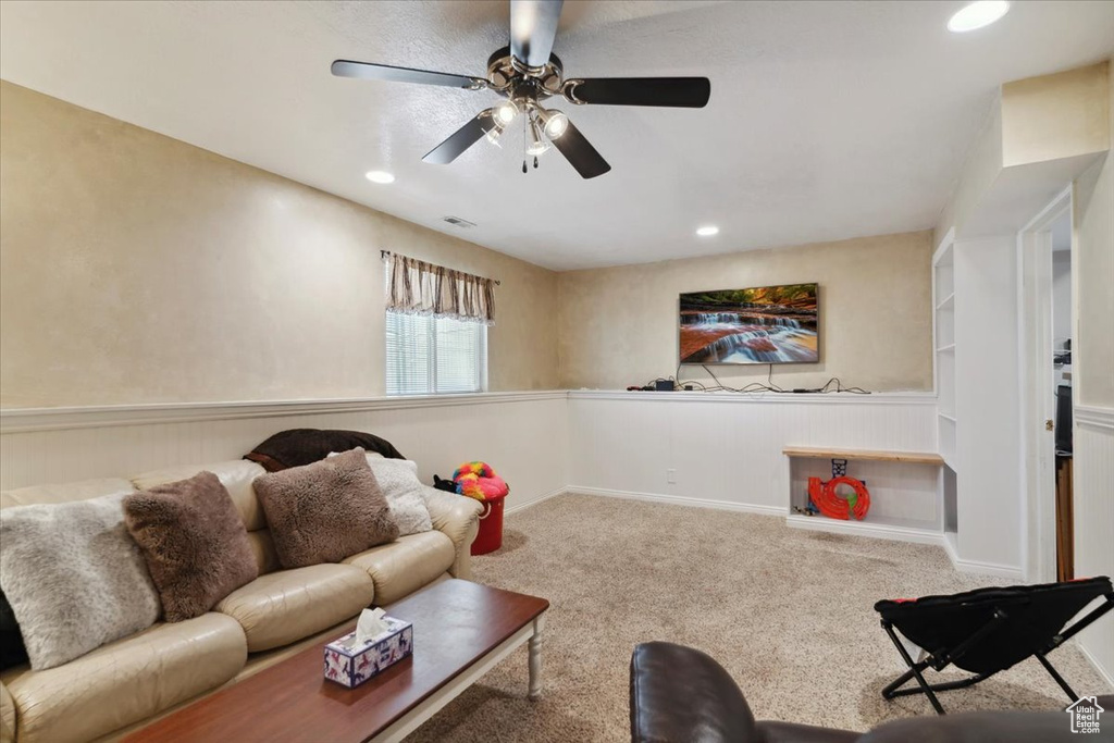 Living area with a ceiling fan, carpet floors, recessed lighting, and wainscoting