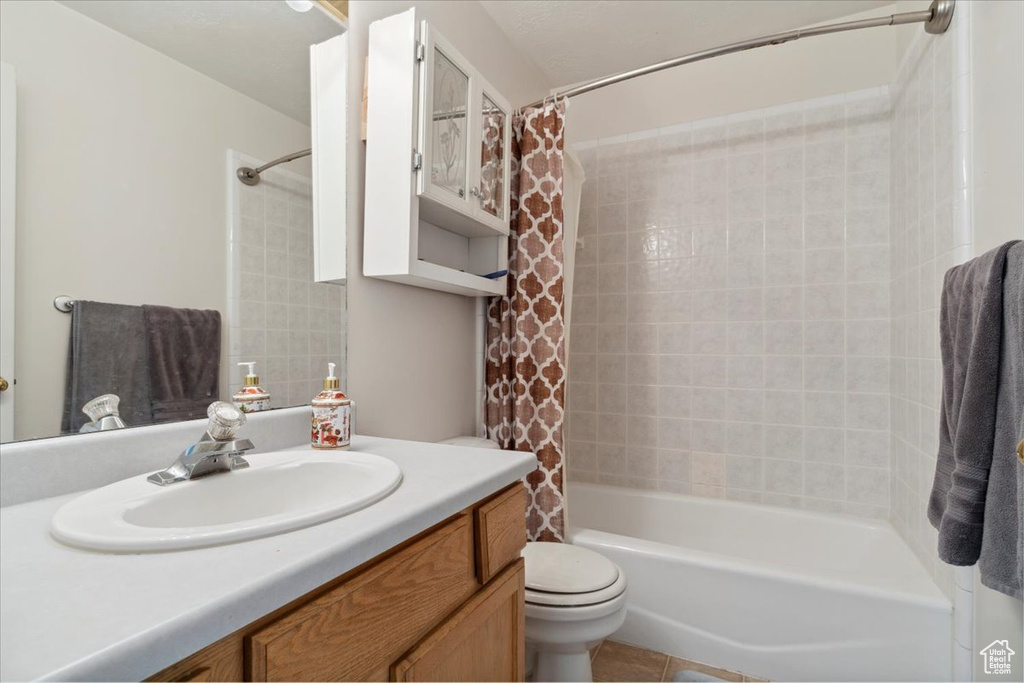 Full bath featuring vanity, shower / bathtub combination with curtain, toilet, and tile patterned floors