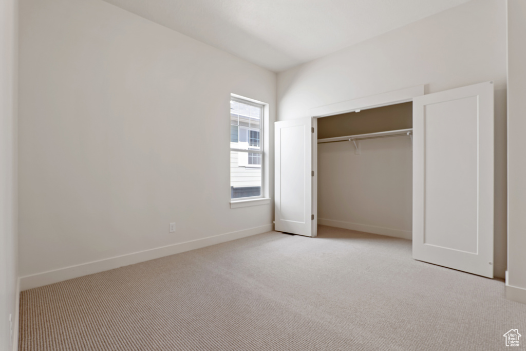 Unfurnished bedroom with carpet flooring, baseboards, and a closet