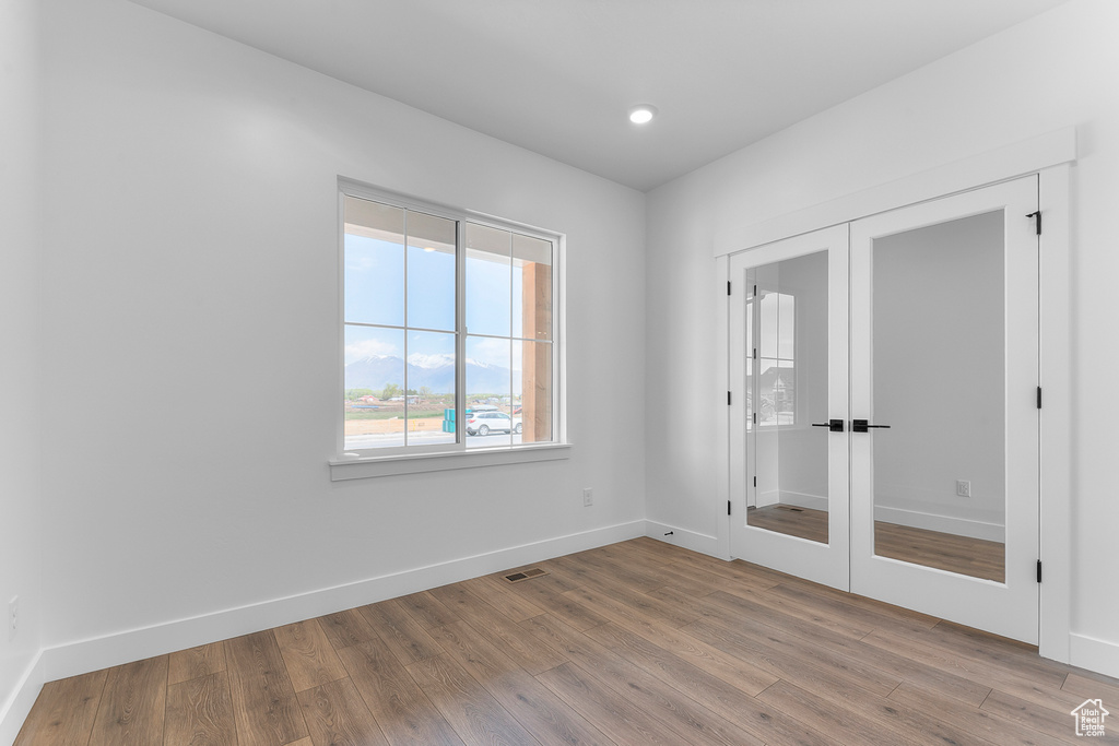 Spare room featuring french doors, wood finished floors, baseboards, and recessed lighting