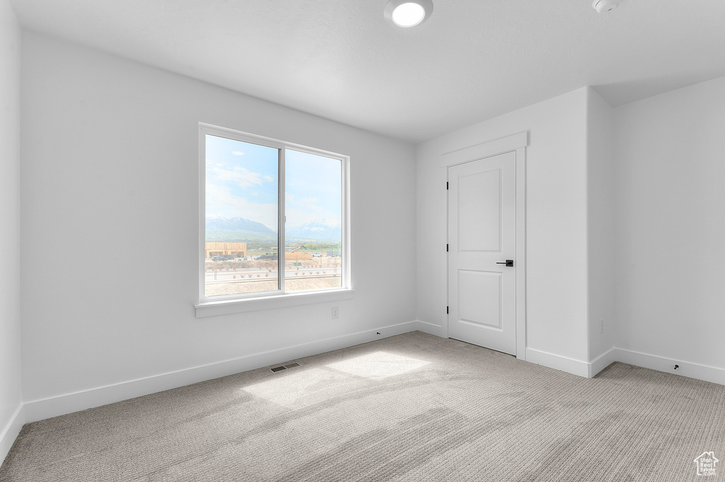 Unfurnished bedroom with light carpet and baseboards