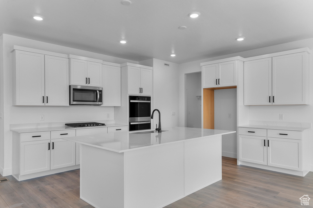 Kitchen with stainless steel microwave, gas cooktop, a sink, light wood-style floors, and recessed lighting