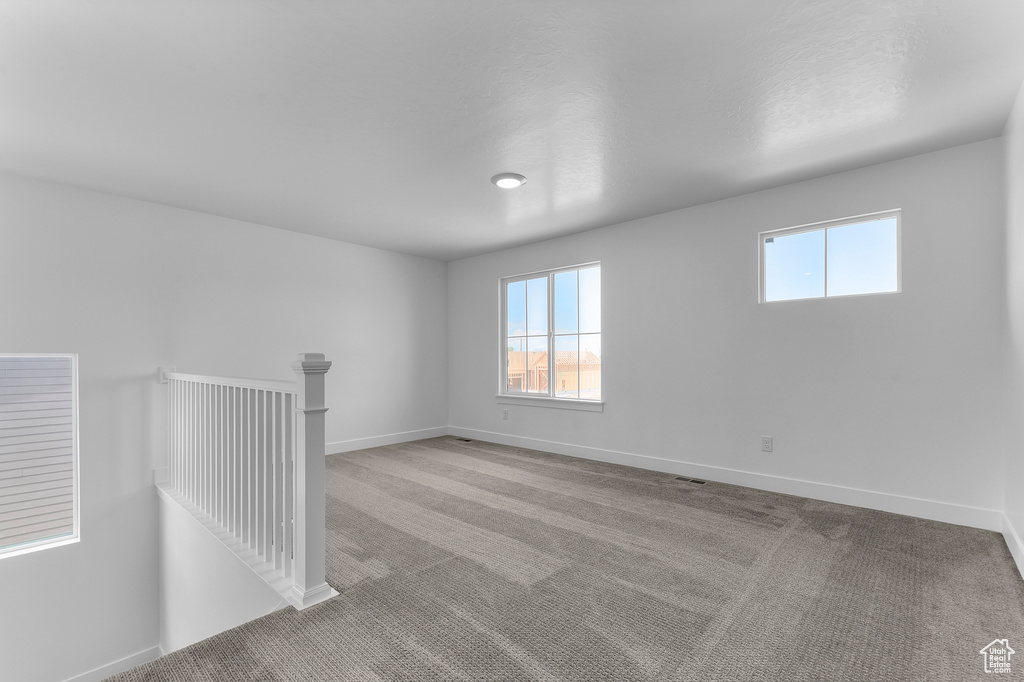 Unfurnished room with carpet, plenty of natural light, and baseboards