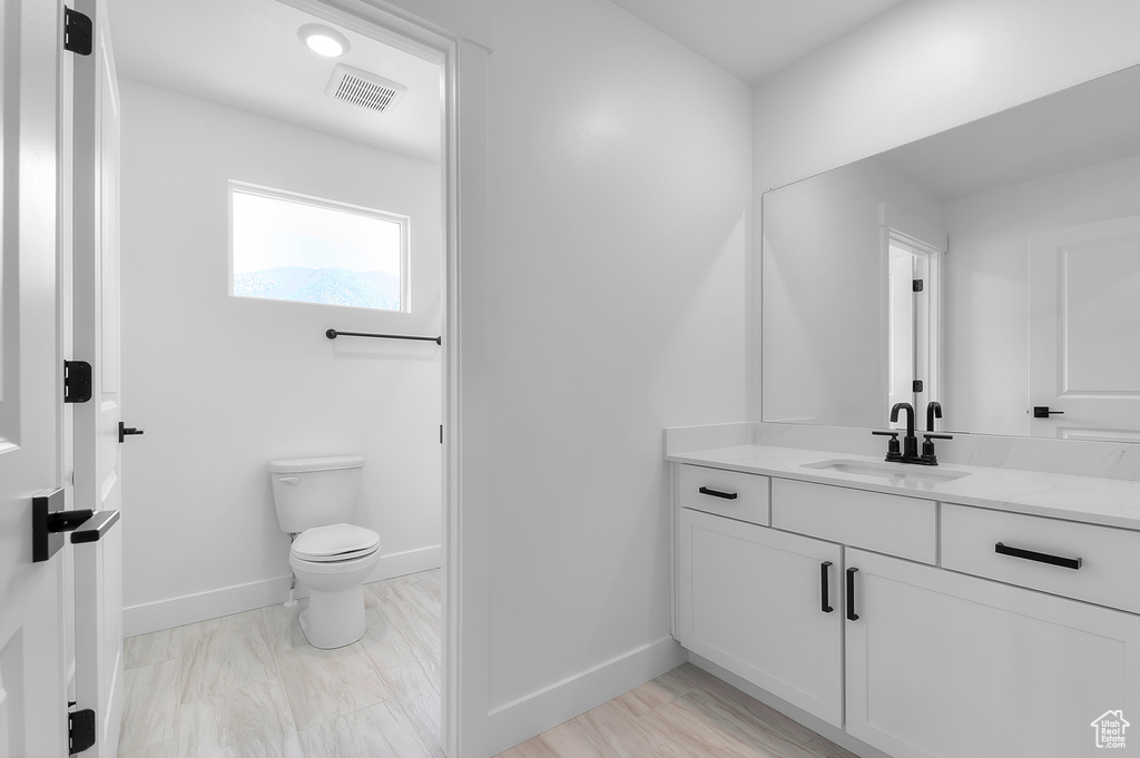 Bathroom featuring vanity, toilet, and baseboards