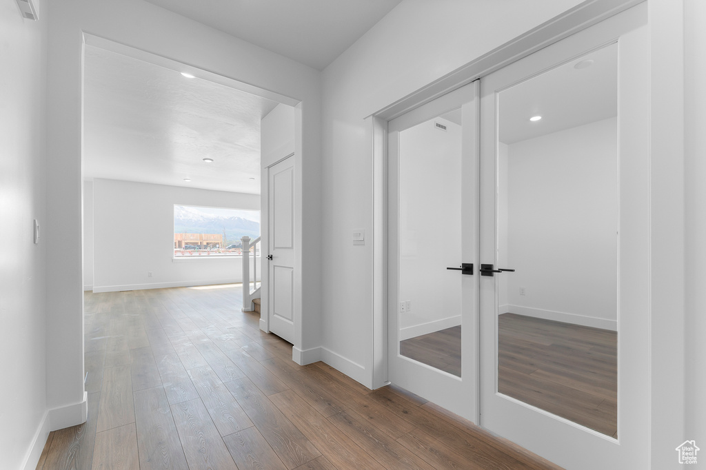 Hall with wood finished floors, baseboards, and recessed lighting