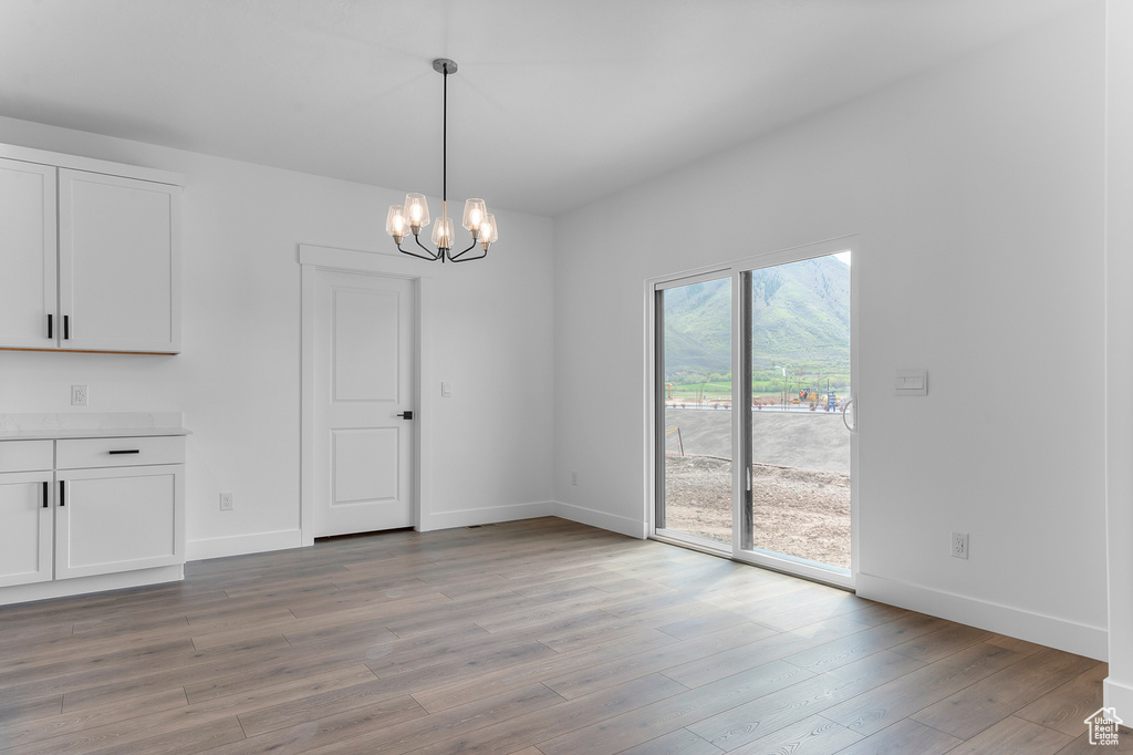 Unfurnished dining area with light wood-style floors, baseboards, and a chandelier