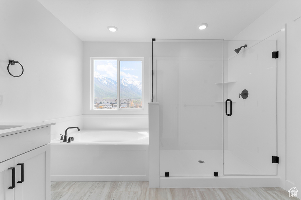 Bathroom featuring a garden tub, a stall shower, and vanity