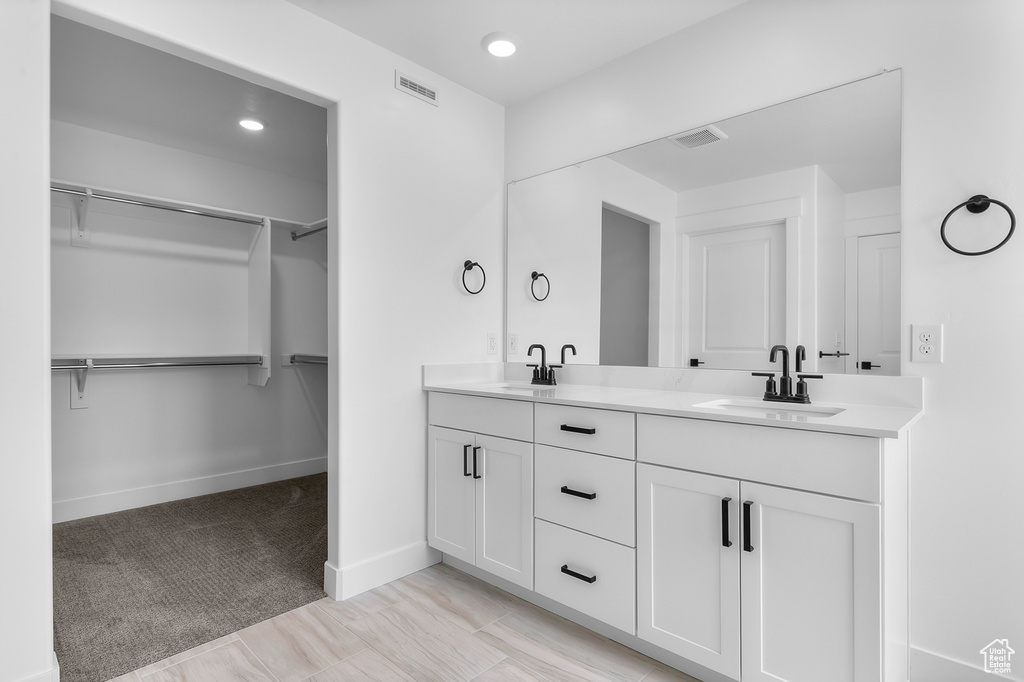 Bathroom featuring double vanity, a spacious closet, baseboards, and recessed lighting