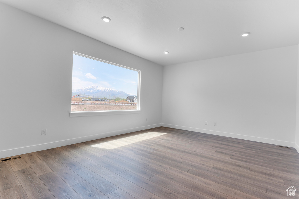Empty room featuring wood finished floors, baseboards, recessed lighting, and a mountain view