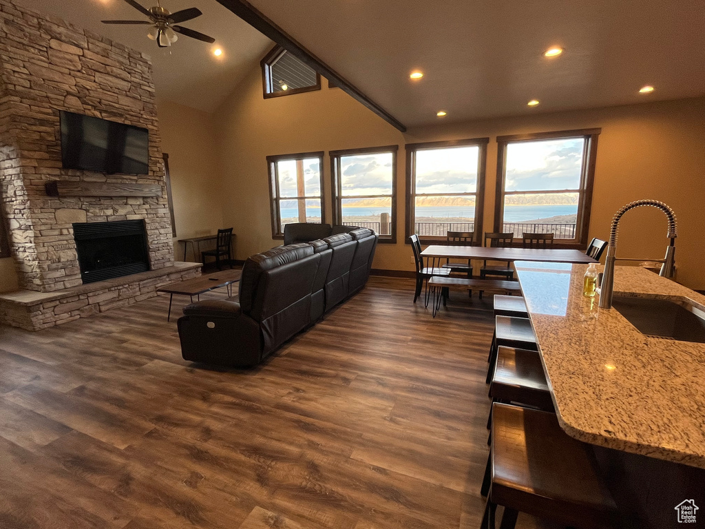 Living room featuring ceiling fan, healthy amount of natural light, a stone fireplace, dark wood-style floors, and recessed lighting