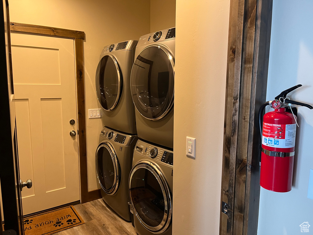 Laundry area featuring stacked washing machine and dryer and wood finished floors