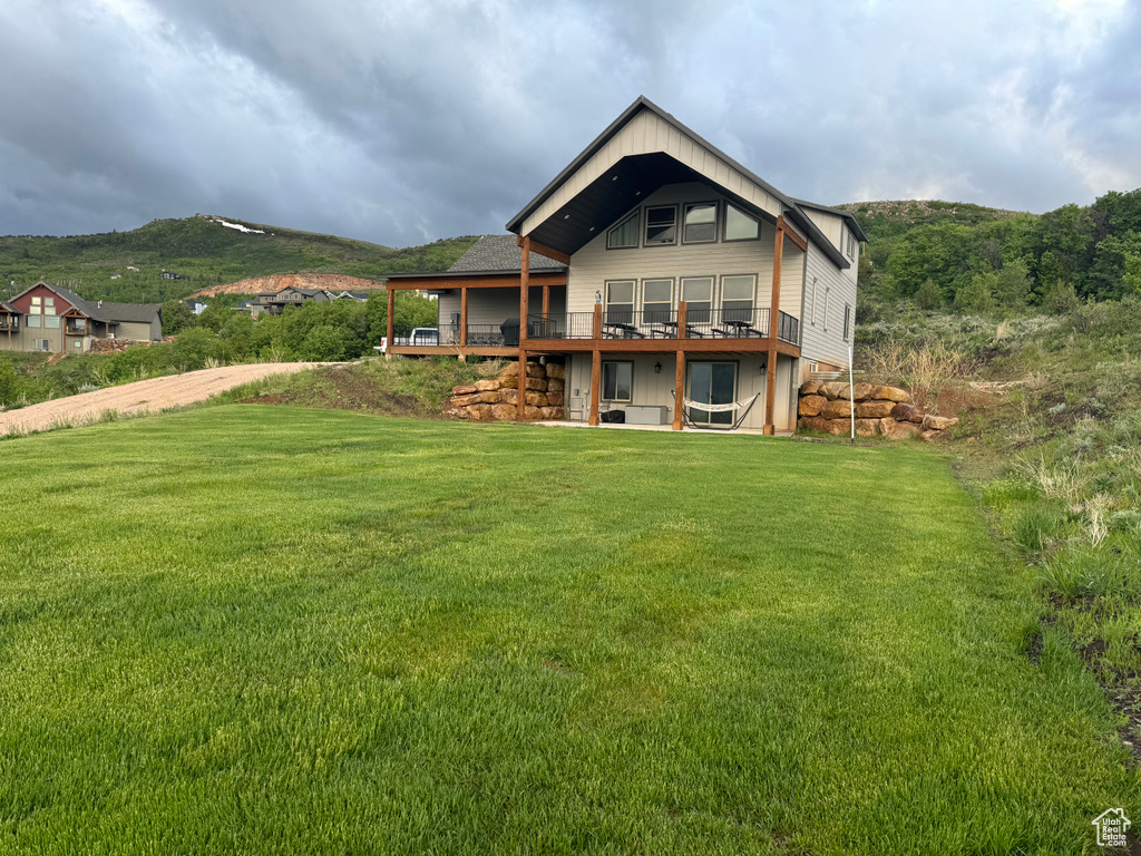 Back of property with a deck with mountain view and a yard